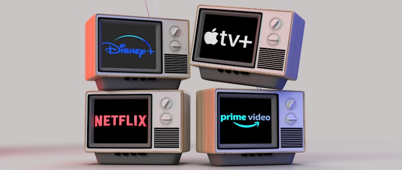 Four old-style television sets are stacked in two rows and each screen displays a different streaming service logo: Disney+, Apple TV+, Netflix, and Prime Video.